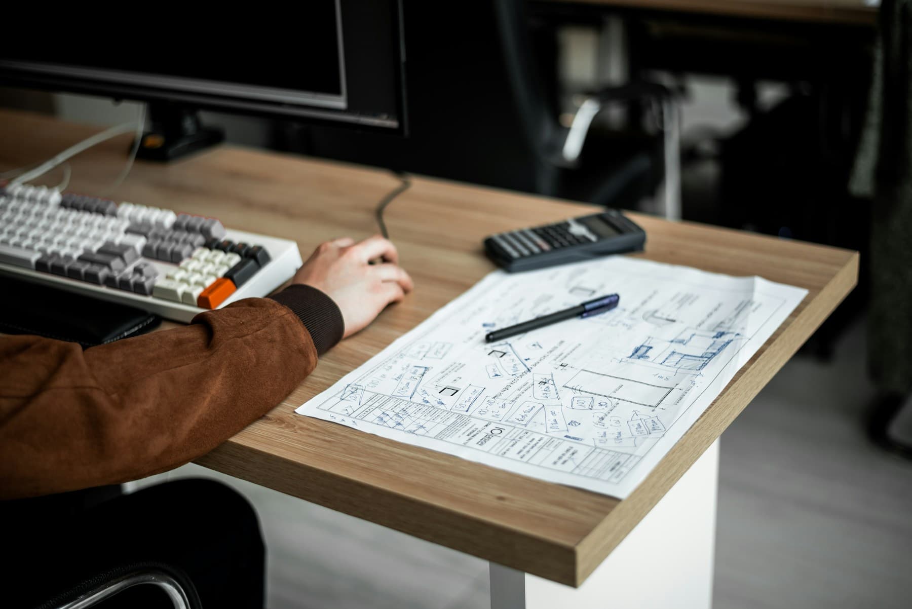 Person working at a desk with a calculator and computer keyboard