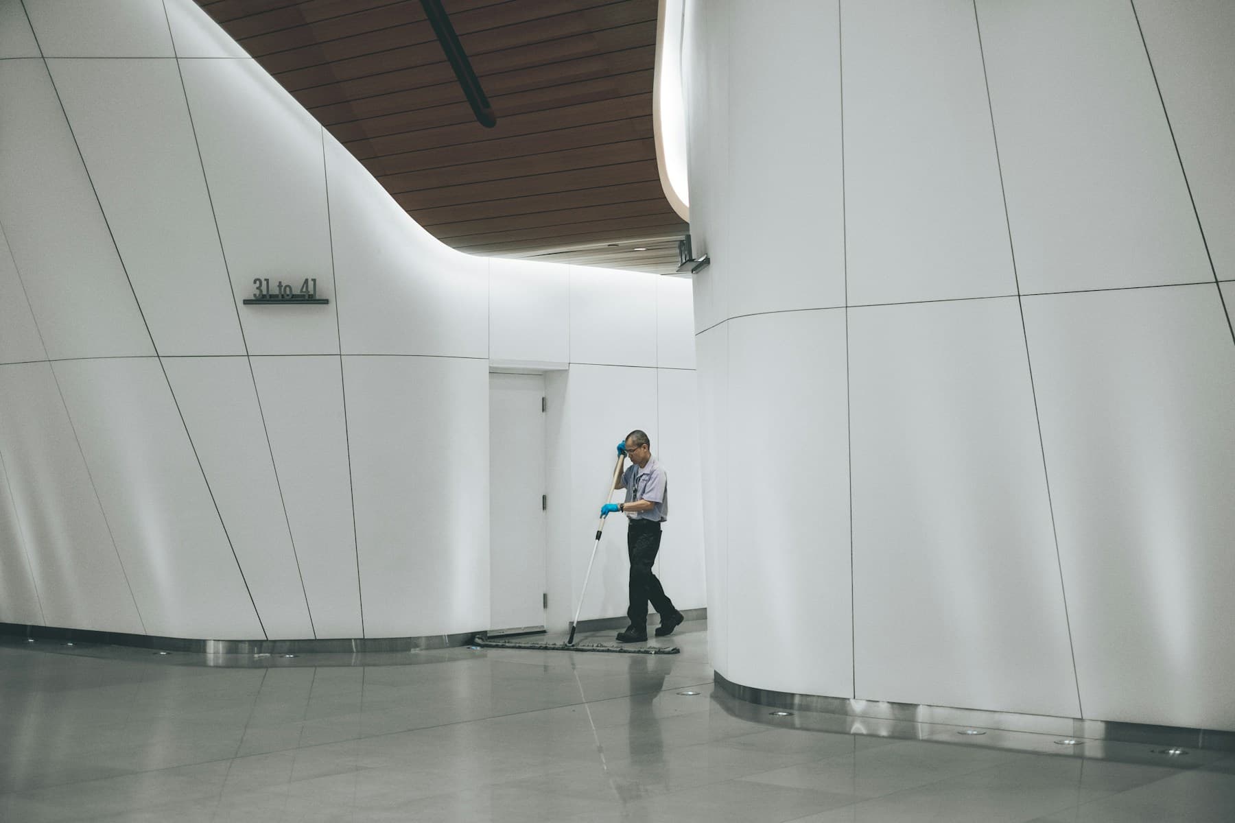 Cleaner working along a quiet office hallway